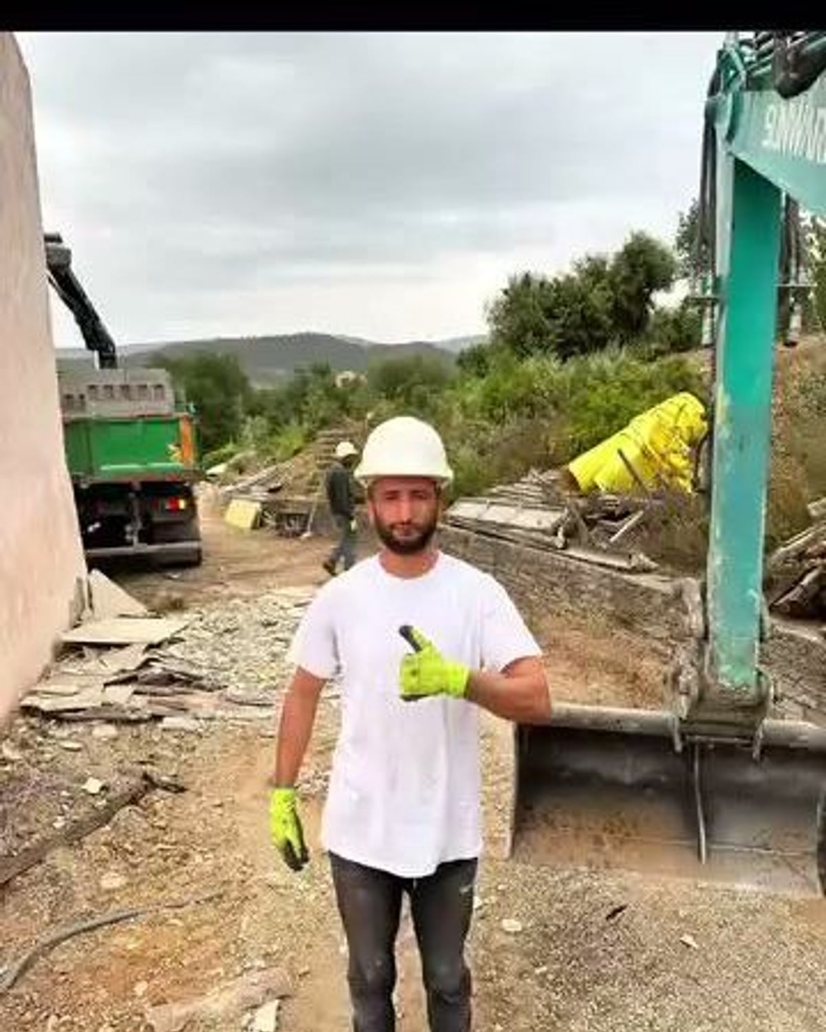 Membre de l'équipe EHD Jardins d'Azur en casque de chantier, devant la pelle mécanique, à Cogolin