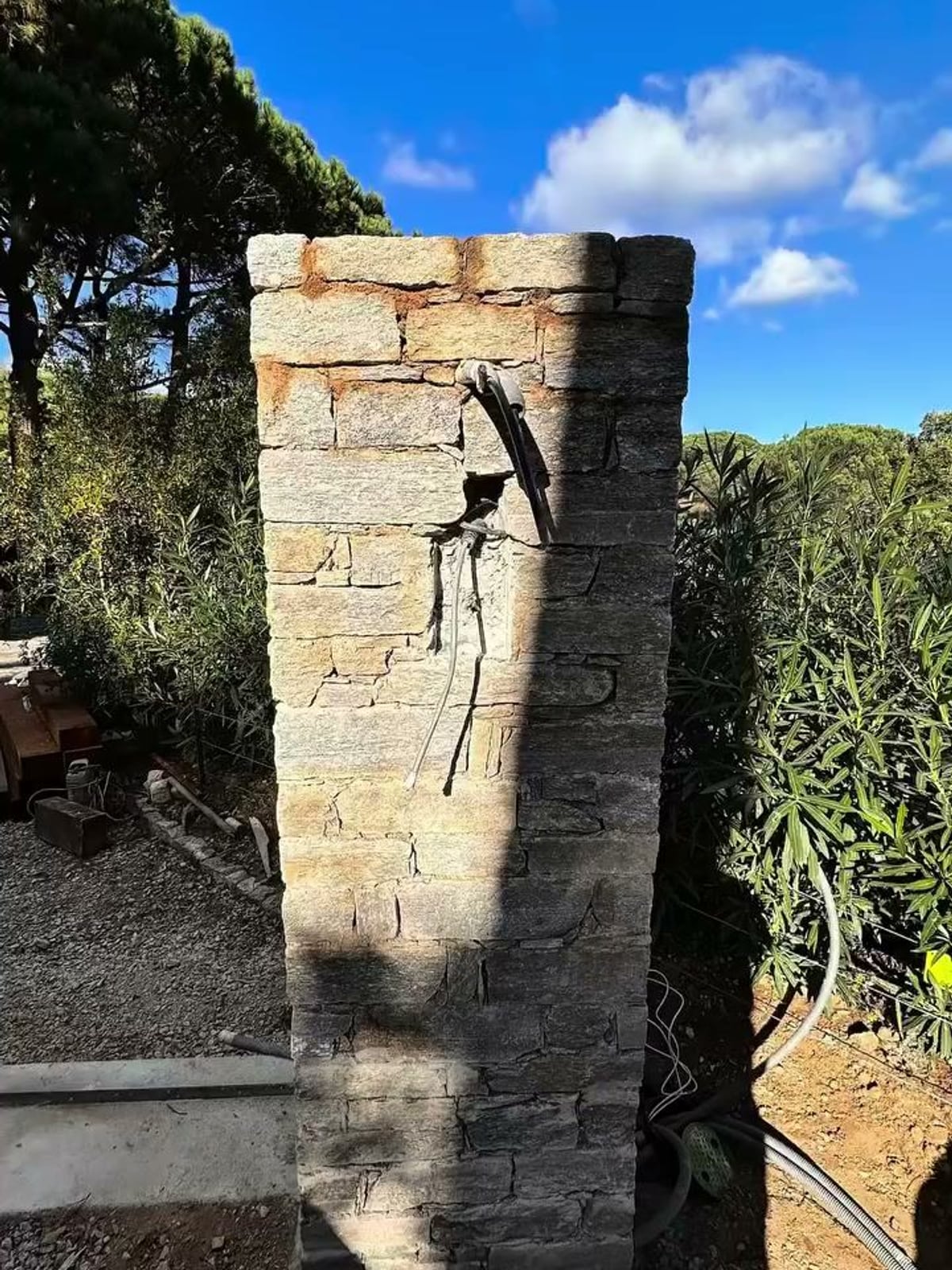 Poteau de portail en pierre naturelle terminé, sous le ciel bleu