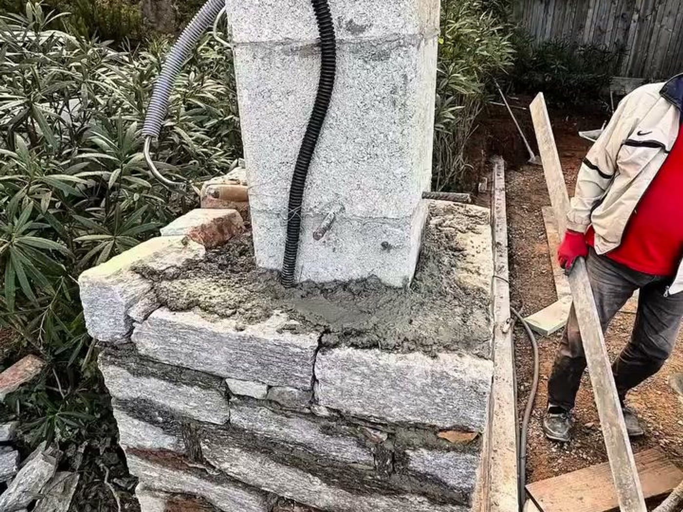 Poteau de portail en pierre naturelle en cours de montage, gaine électrique en attente
