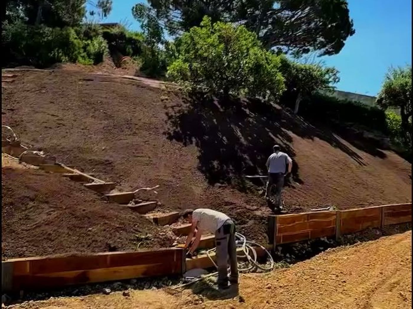Mur de soutènement en traverses paysagères et marches dans un jardin en cours d'aménagement