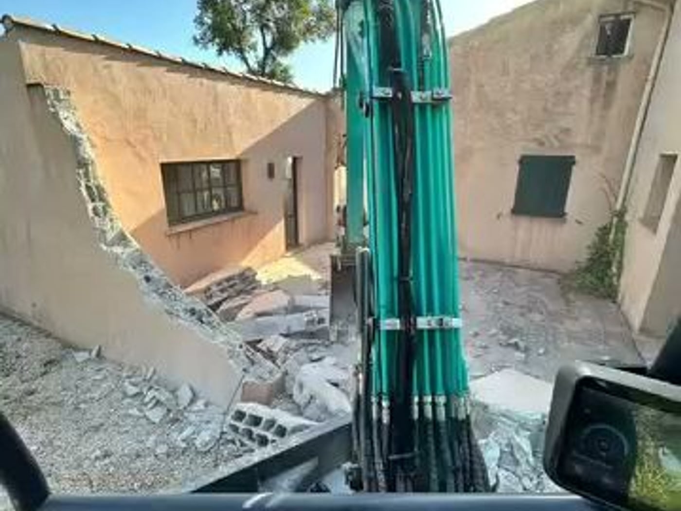 Pelle mécanique en cours de démolition d'un mur de la maison incendiée, à Cogolin